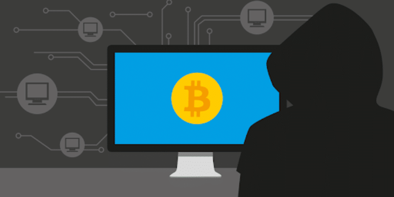 Crypto Jacker infront of computer with a bitcon iconon screen